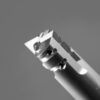 Black and white close-up photograph of precision end mill or machining tool showing detailed cutting edges, fluted geometry, and cylindrical shaft with sharp geometric cutting surfaces