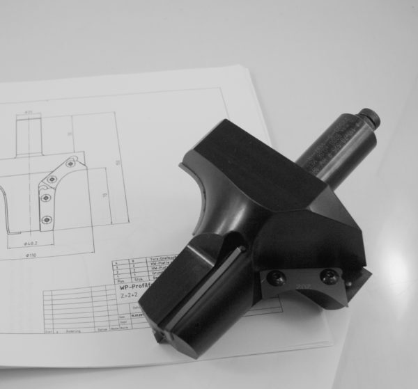 Precision machined metal tool holder or cutting tool insert positioned on detailed engineering drawings and technical schematics with dimensional specifications